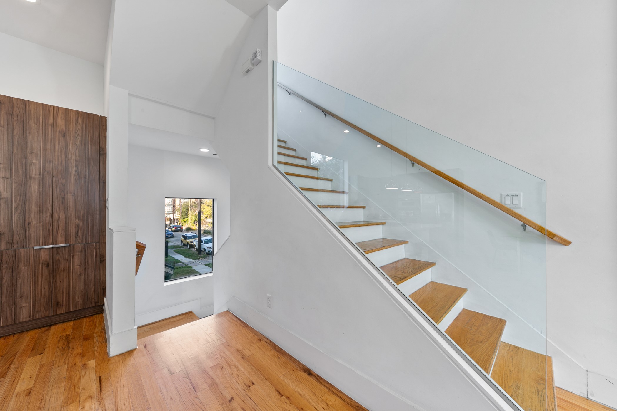 604 Oakley Street Houston, TX 77006 - Photo 7 of 38 Modern staircase design with glass railing and warm wood floors creates a sleek, urban aesthetic.