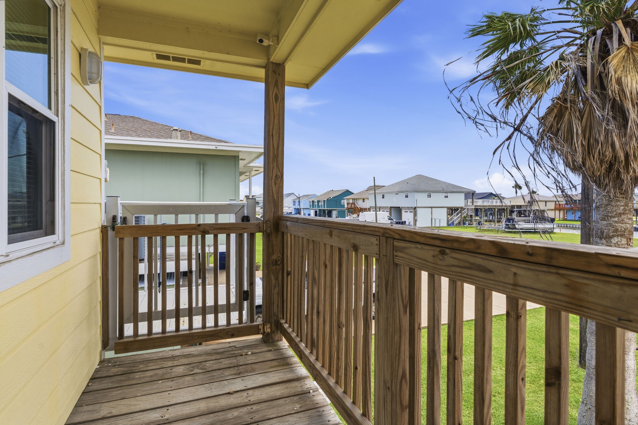 119 Sand Shoals Road Freeport, TX 77541 - Photo 33 of 34 Side balcony off the kitchen — covered wood deck with cargo lift access at the railing for hauling groceries, coolers, and gear directly up from ground level. Open neighborhood views to the side and palm-shaded eastern exposure.