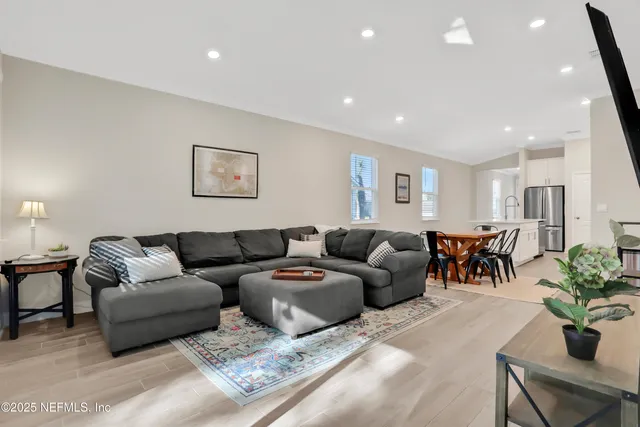 a living room with furniture potted plant and kitchen view