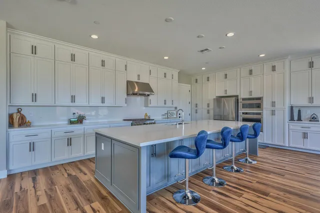 a kitchen with stainless steel appliances granite countertop a stove a refrigerator and a white cabinets