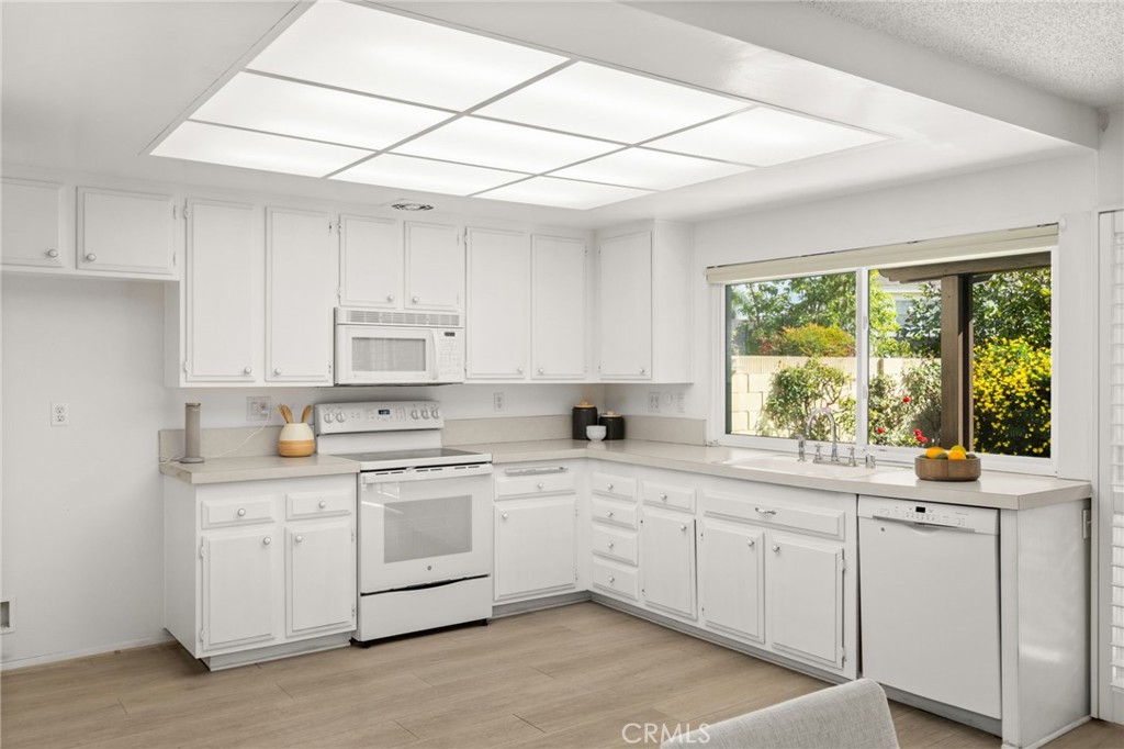 8242 Baldwin Circle Buena Park, CA 90621 - Photo 10 of 44 a kitchen with white cabinets appliances a sink and a window