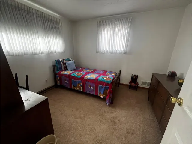 a bedroom with a bed and a flat tv screen on the dresser