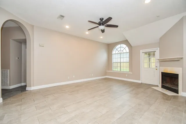 an empty room with windows and fireplace