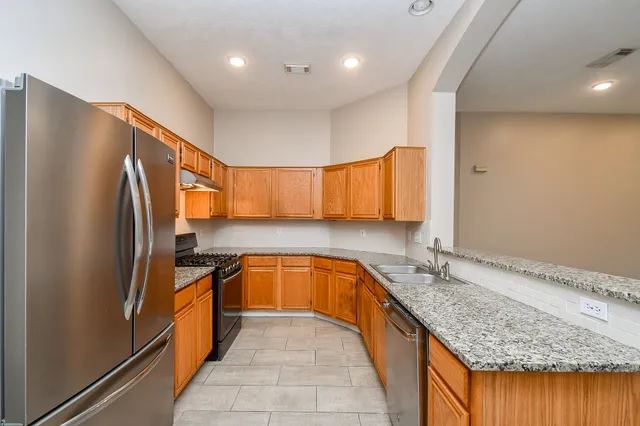 a kitchen with stainless steel appliances granite countertop a refrigerator a stove and a sink