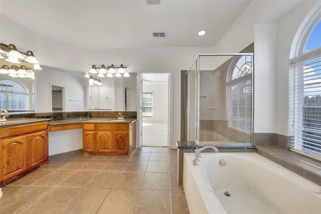 a large spacious bathroom with a tub sink shower and mirror