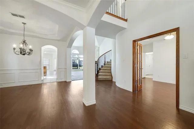 a view of a hallway with wooden floor and a chandelier