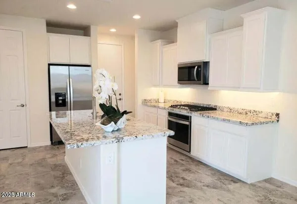 a kitchen with kitchen island granite countertop appliances cabinets and a counter top space