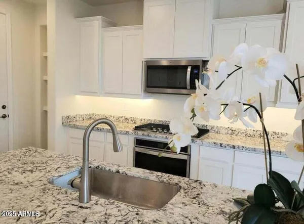 a kitchen with a stove a faucet and cabinets