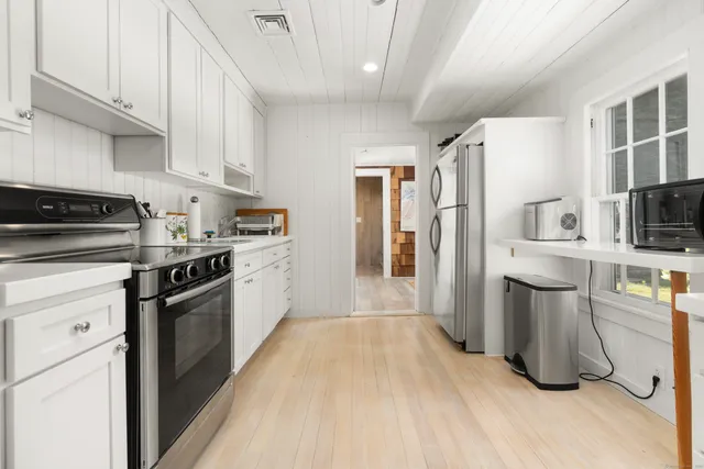 a kitchen with stainless steel appliances a sink a stove a refrigerator cabinets and a window
