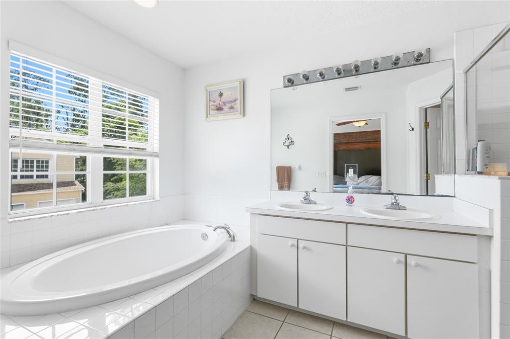 6216 Rosefinch Court, Unit 102 Lakewood Ranch, FL 34202 - Photo 18 of 45 a bathroom with a tub a sink a mirror a window and a shower