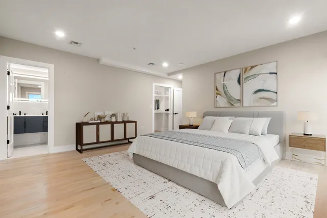 a spacious bedroom with a bed and painting on wall