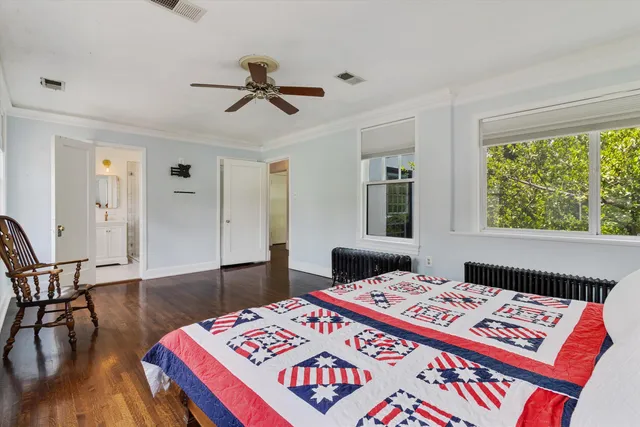 a bedroom with a bed and a lamp on table with wooden floor