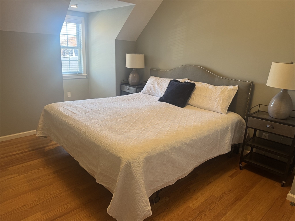 56 Eliot Street, Unit C Natick, MA 01760 - Photo 14 of 21 a large bed sitting in a bedroom next to a lamp