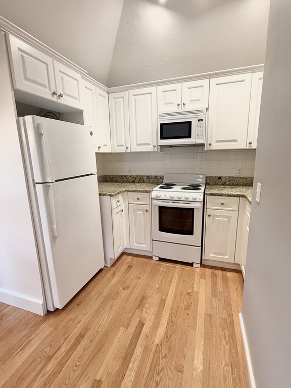56 Eliot Street, Unit C Natick, MA 01760 - Photo 5 of 21 a kitchen with granite countertop white cabinets and white appliances