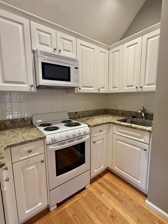 56 Eliot Street, Unit C Natick, MA 01760 - Photo 6 of 21 a kitchen with white cabinets stainless steel appliances and sink