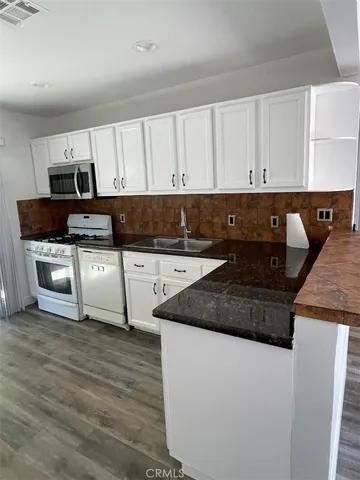 a kitchen with granite countertop a sink a stove and cabinets