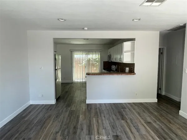wooden floor in kitchen and an empty room with wooden floor