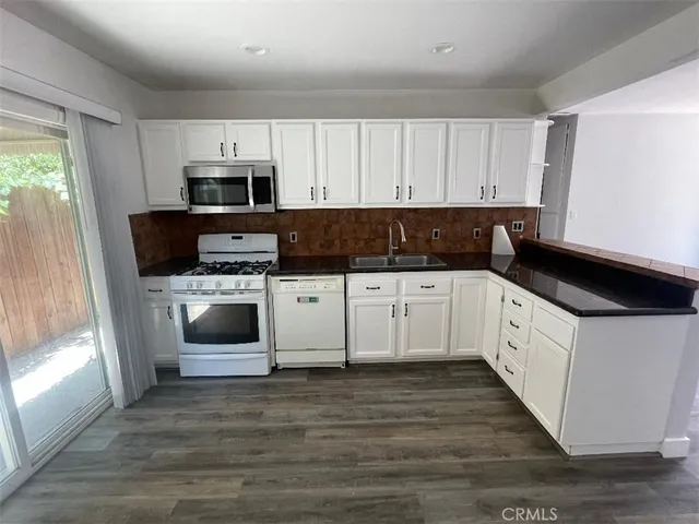 a kitchen with granite countertop a sink a stove and cabinets