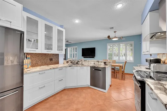 a kitchen with stainless steel appliances granite countertop a stove top oven a sink dishwasher a refrigerator and white cabinets with wooden floor