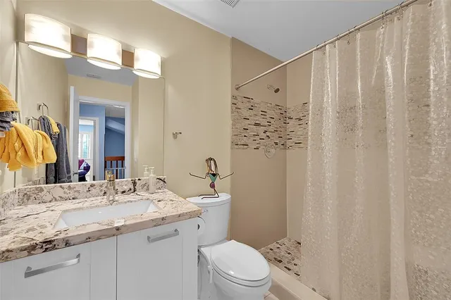 a bathroom with a granite countertop sink a toilet and shower