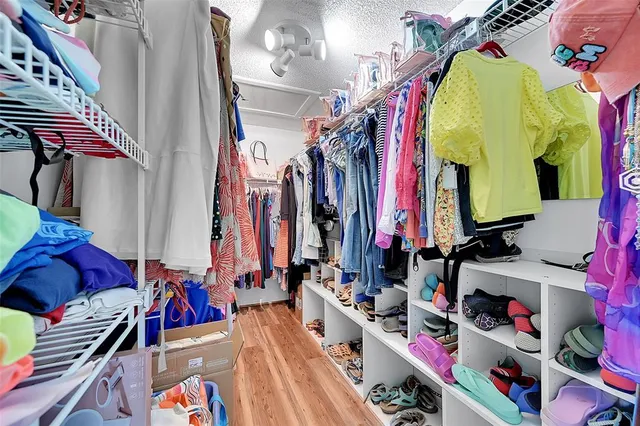 a view of walk in closet with clothes and shoes