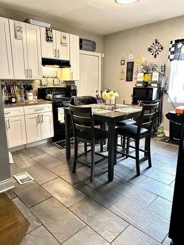 a kitchen with stainless steel appliances a sink a stove a table and chairs