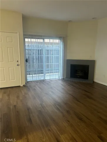 a view of empty room with wooden floor and fireplace