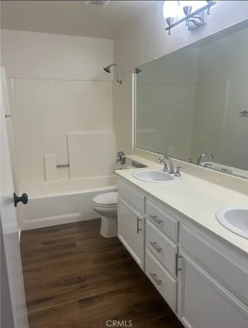 a bathroom with a double vanity sink a toilet and a tub