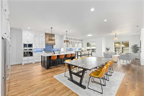 a kitchen with stainless steel appliances granite countertop a sink a stove a refrigerator and chairs