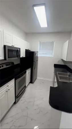a kitchen with granite countertop white cabinets and black appliances