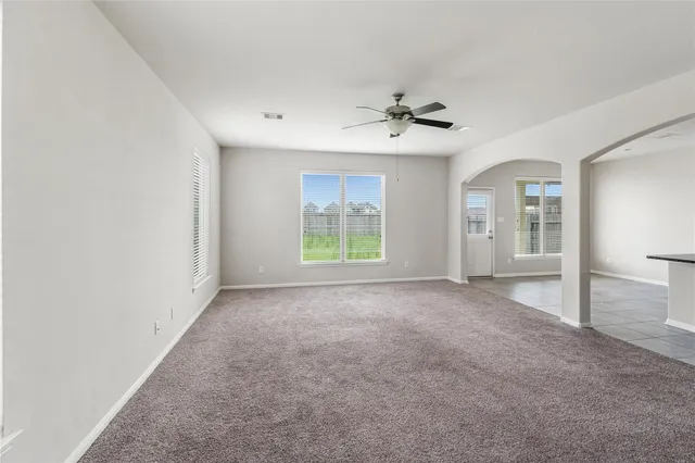 a view of a big room with windows and chandelier fan