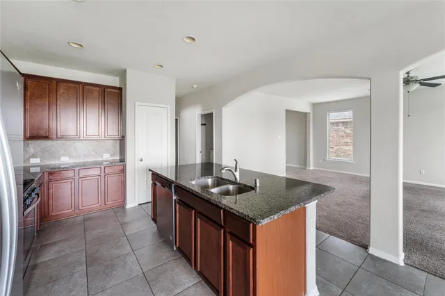 a kitchen with kitchen island granite countertop a sink stove and cabinets