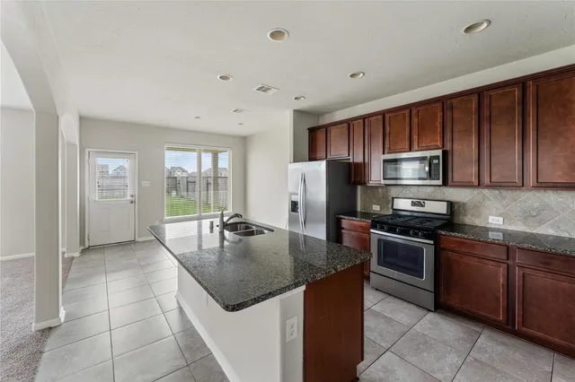 a kitchen with stainless steel appliances granite countertop a stove a sink a microwave and a refrigerator