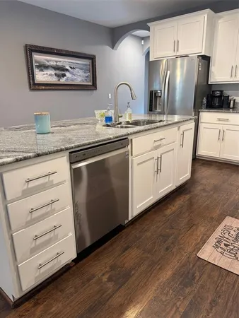 a kitchen with granite countertop white cabinets and stainless steel appliances