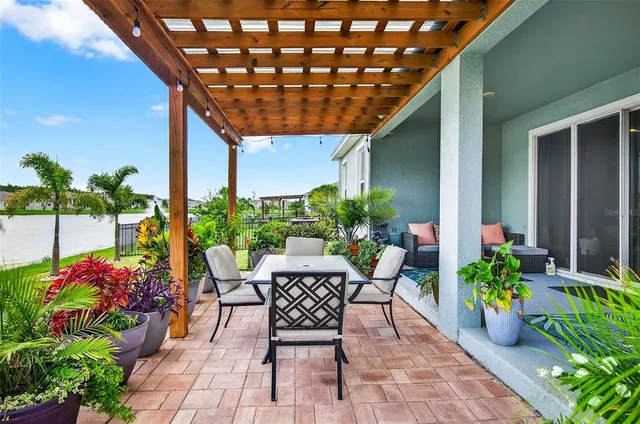 a patio with table and chairs potted plants