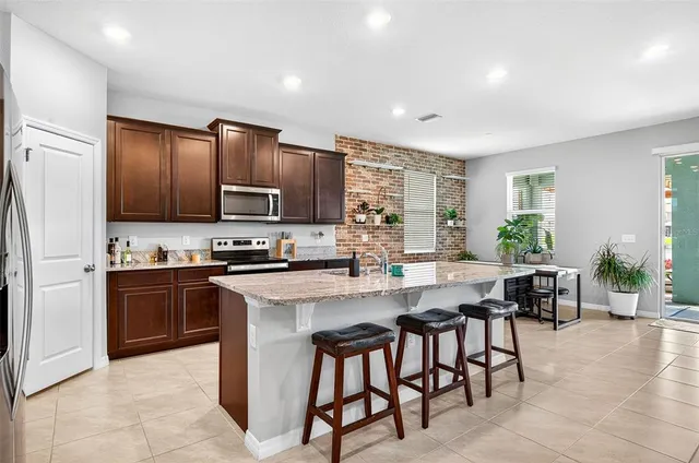 a kitchen with microwave a refrigerator and chairs