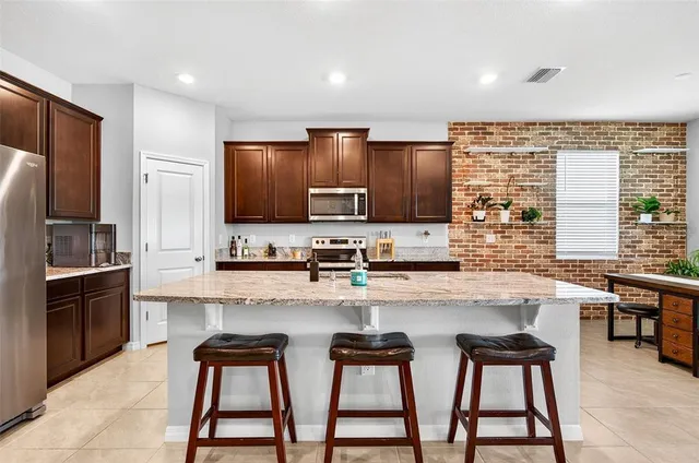 a kitchen with stainless steel appliances granite countertop a stove a sink dishwasher a refrigerator and a microwave