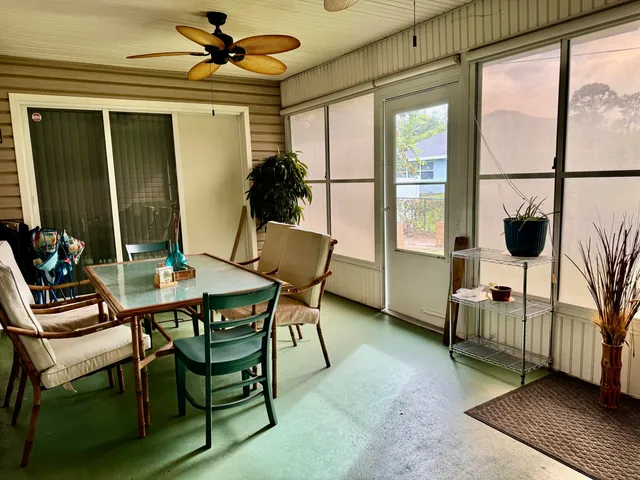 a living room with a table chairs and a ceiling fan