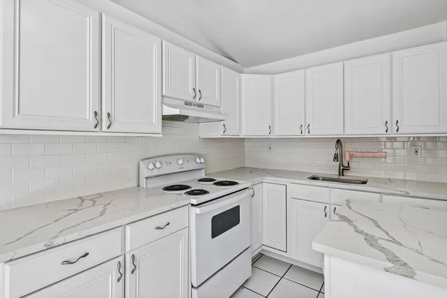 a kitchen with granite countertop white cabinets white stainless steel appliances and sink