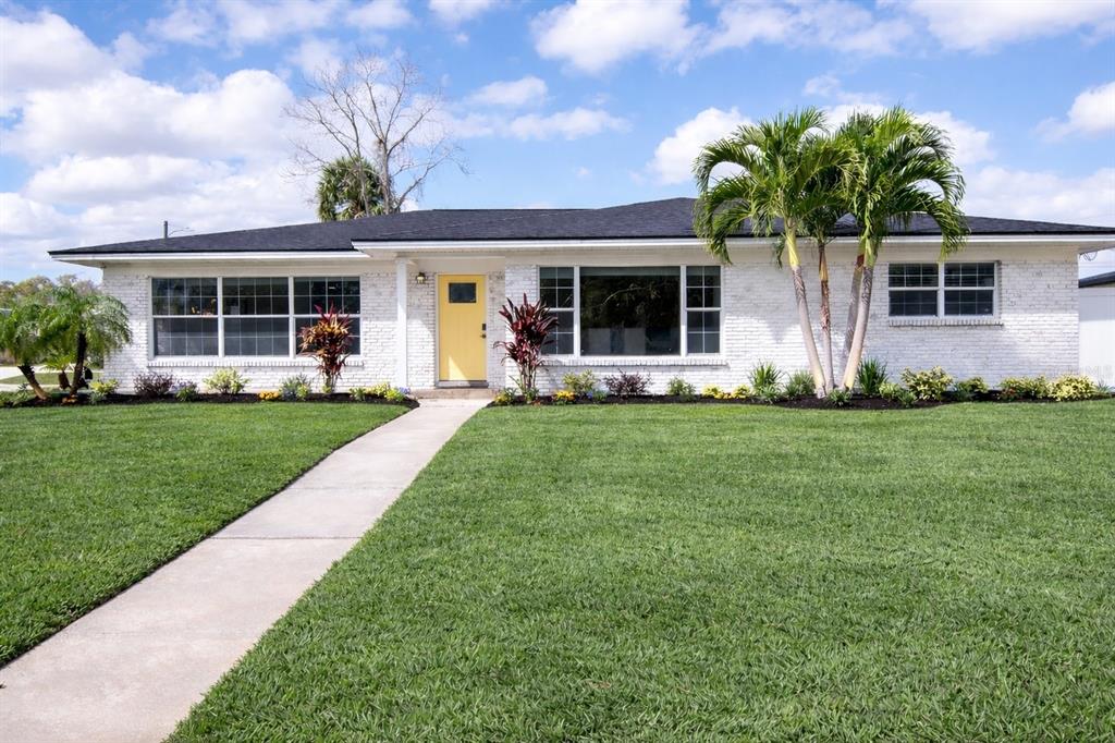 a front view of a house with a yard and potted plants