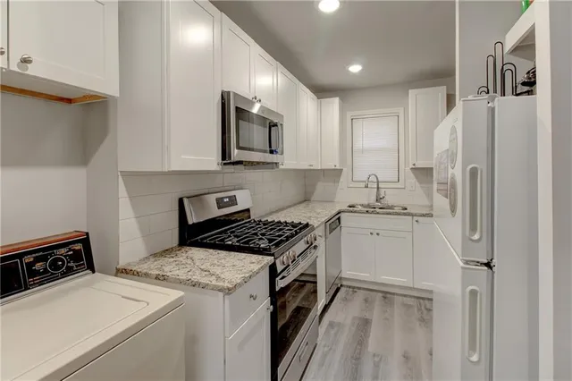a kitchen with granite countertop white cabinets stainless steel appliances and sink