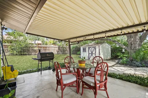 a patio with table and chairs and potted plants