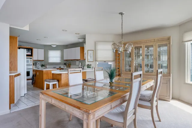 a dining room with stainless steel appliances granite countertop a dining table chairs and a refrigerator