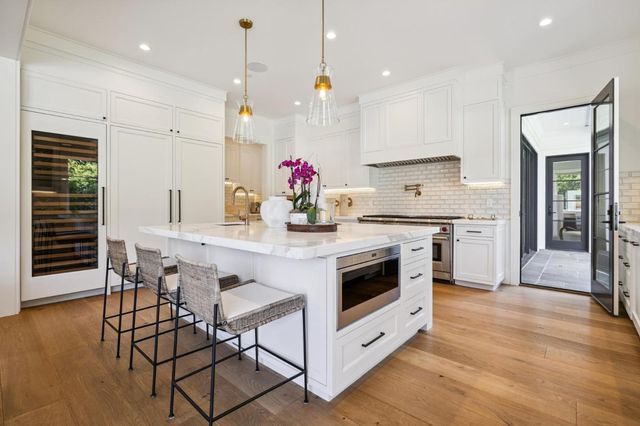 a living room with couches and kitchen view with wooden floor