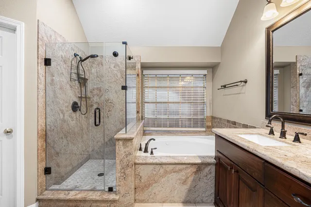 a bathroom with a granite countertop tub sink shower and mirror