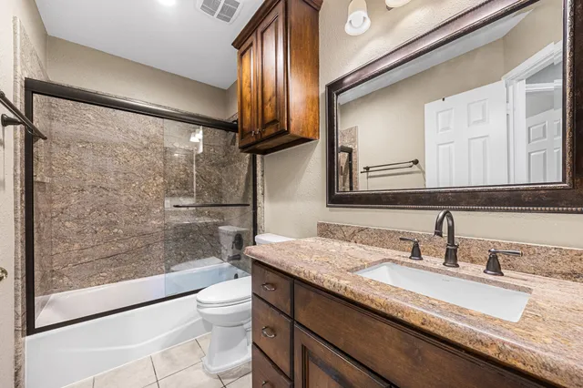a bathroom with a granite countertop sink a toilet a mirror and shower