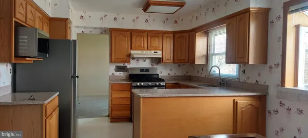 a kitchen with stainless steel appliances granite countertop a stove a sink a refrigerator a counter space and cabinets