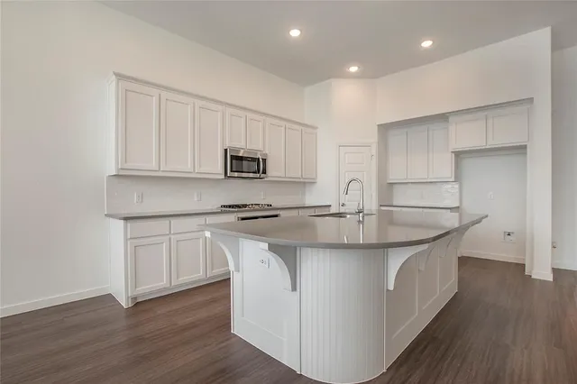 a kitchen with kitchen island granite countertop a sink a stove and cabinets