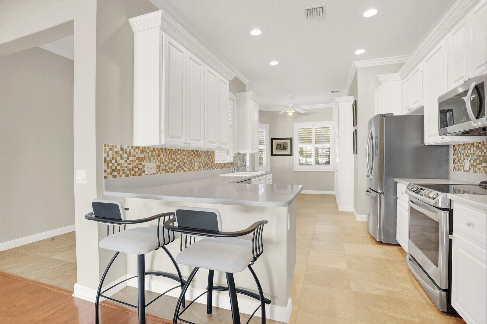 2688 East Community Drive Jupiter, FL 33458 - Photo 11 of 50 a kitchen with stainless steel appliances kitchen island granite countertop a refrigerator and a stove top oven