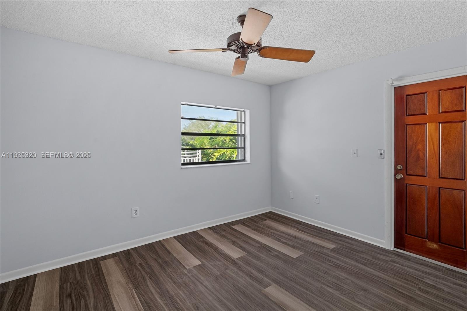 10922 Southwest 25th Street Miami, FL 33165 - Photo 28 of 33 a view of empty room with wooden floor and ceiling fan